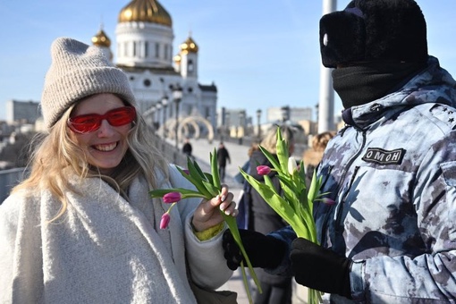 Фото дня: ОМОНовец с закрытым лицом пытается поздравить россиянку с 8 Марта, пока та шарахается от..